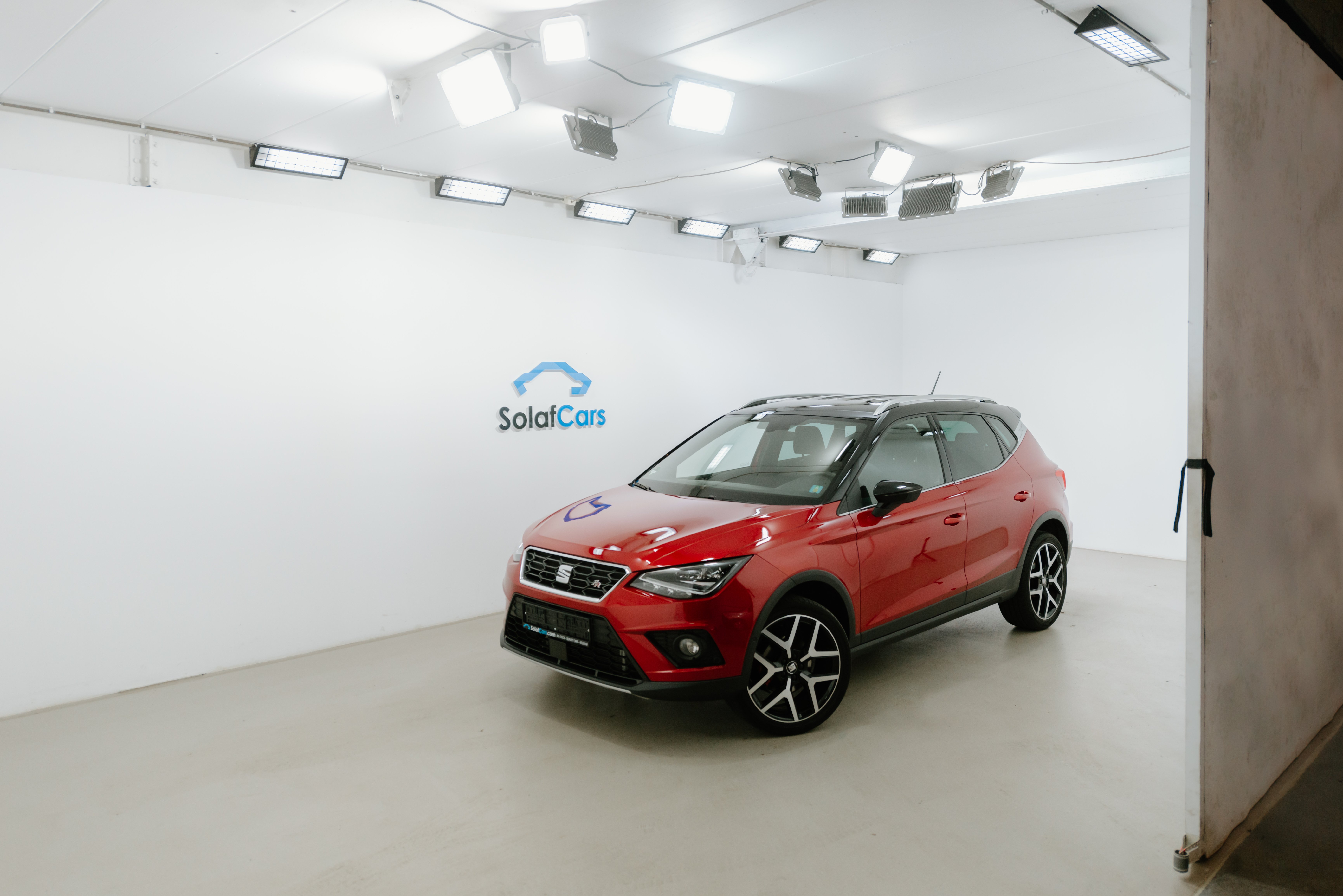 Red car parked in a car dealership photo studio with bright lights