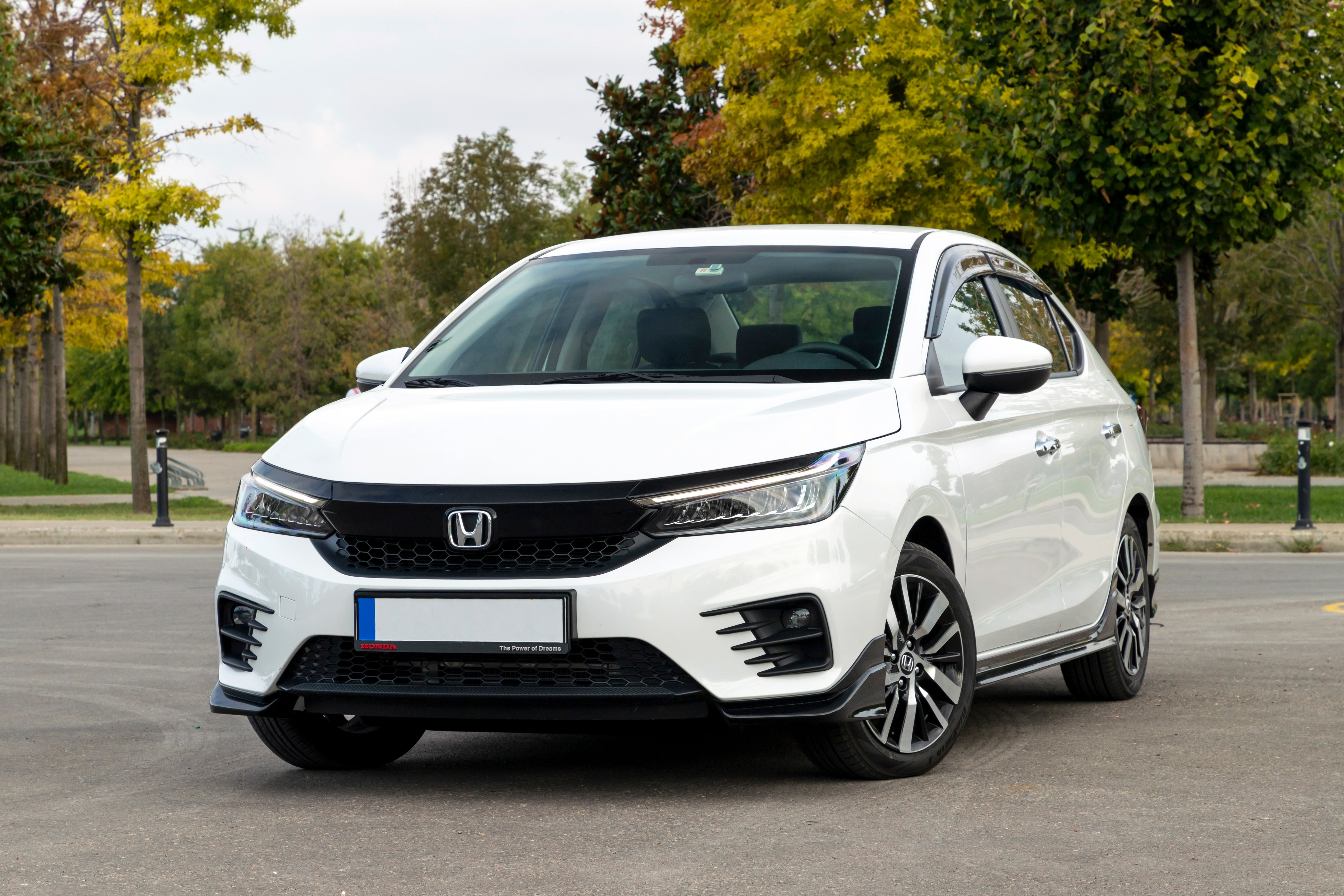 Honda City parked in a park surrounded by green trees